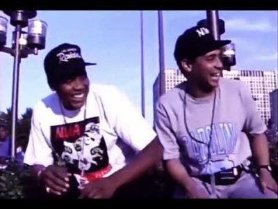 Eazy-E runs past Dre & Yella with an uzi during an interview